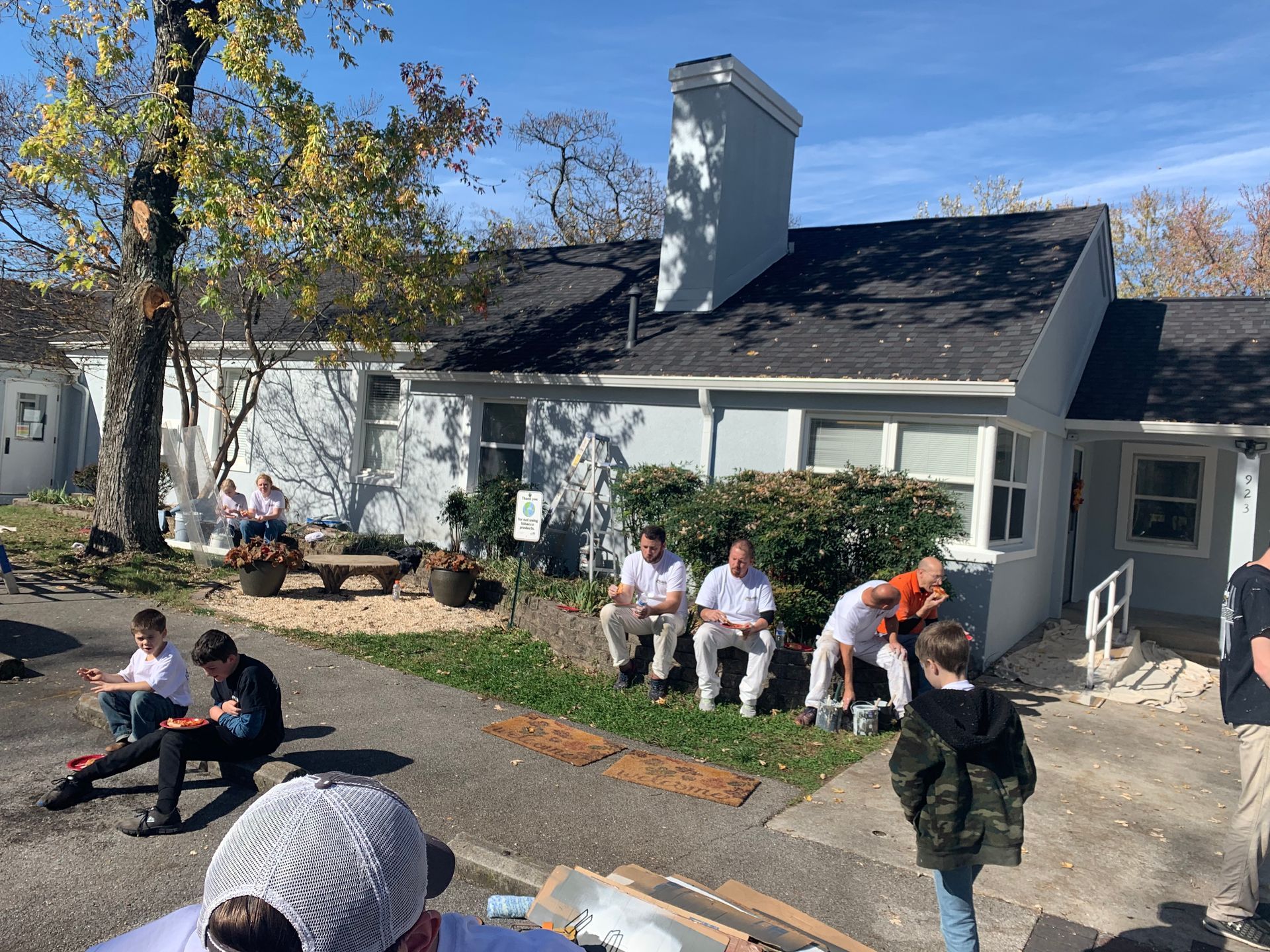 A group of people are sitting in front of a house.