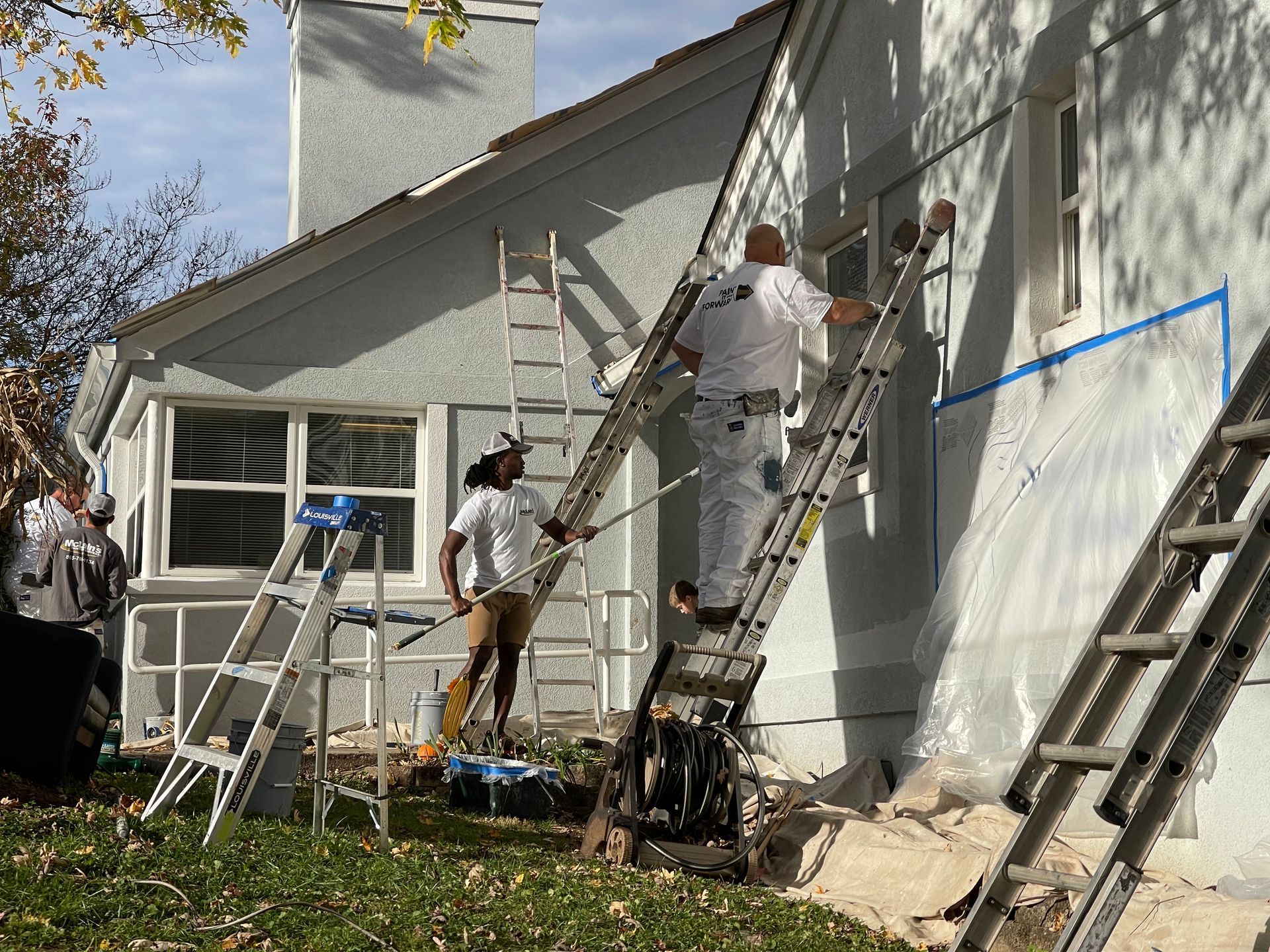 A group of people are painting the side of a house.