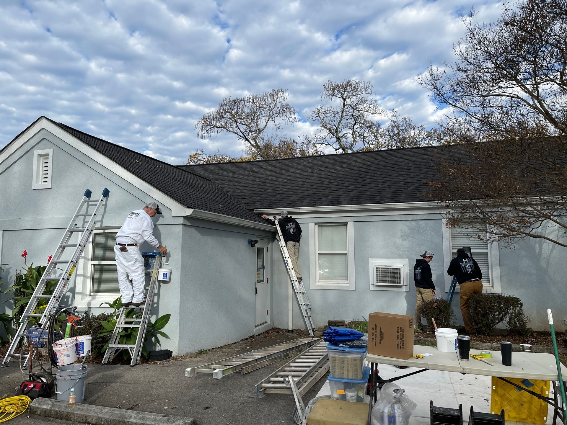 A group of people are painting the side of a house.