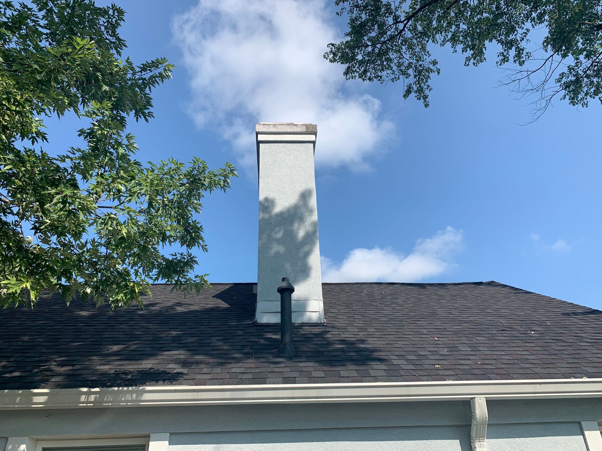 A chimney on the roof of a house with a blue sky in the background.