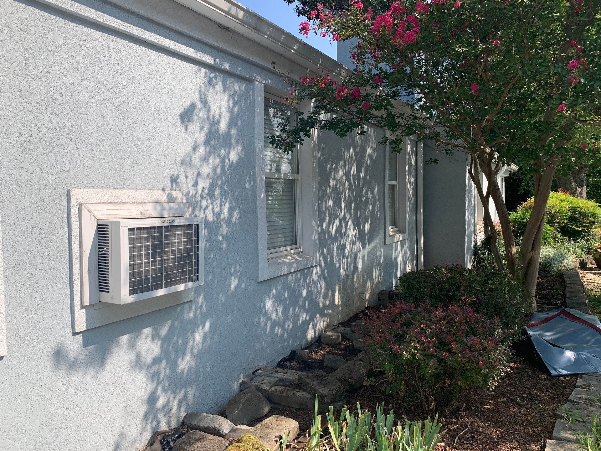 A house with a window air conditioner on the side of it.
