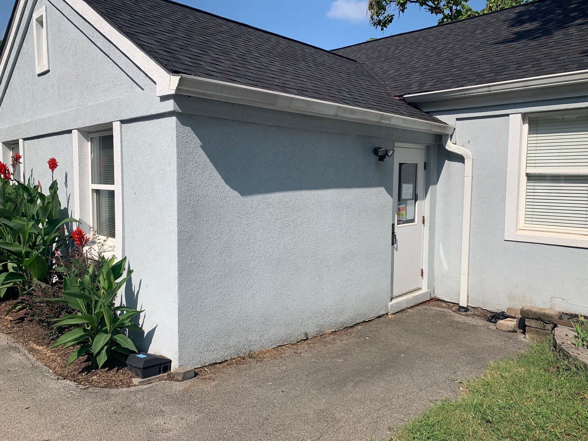 A small white house with a black roof and a white door.