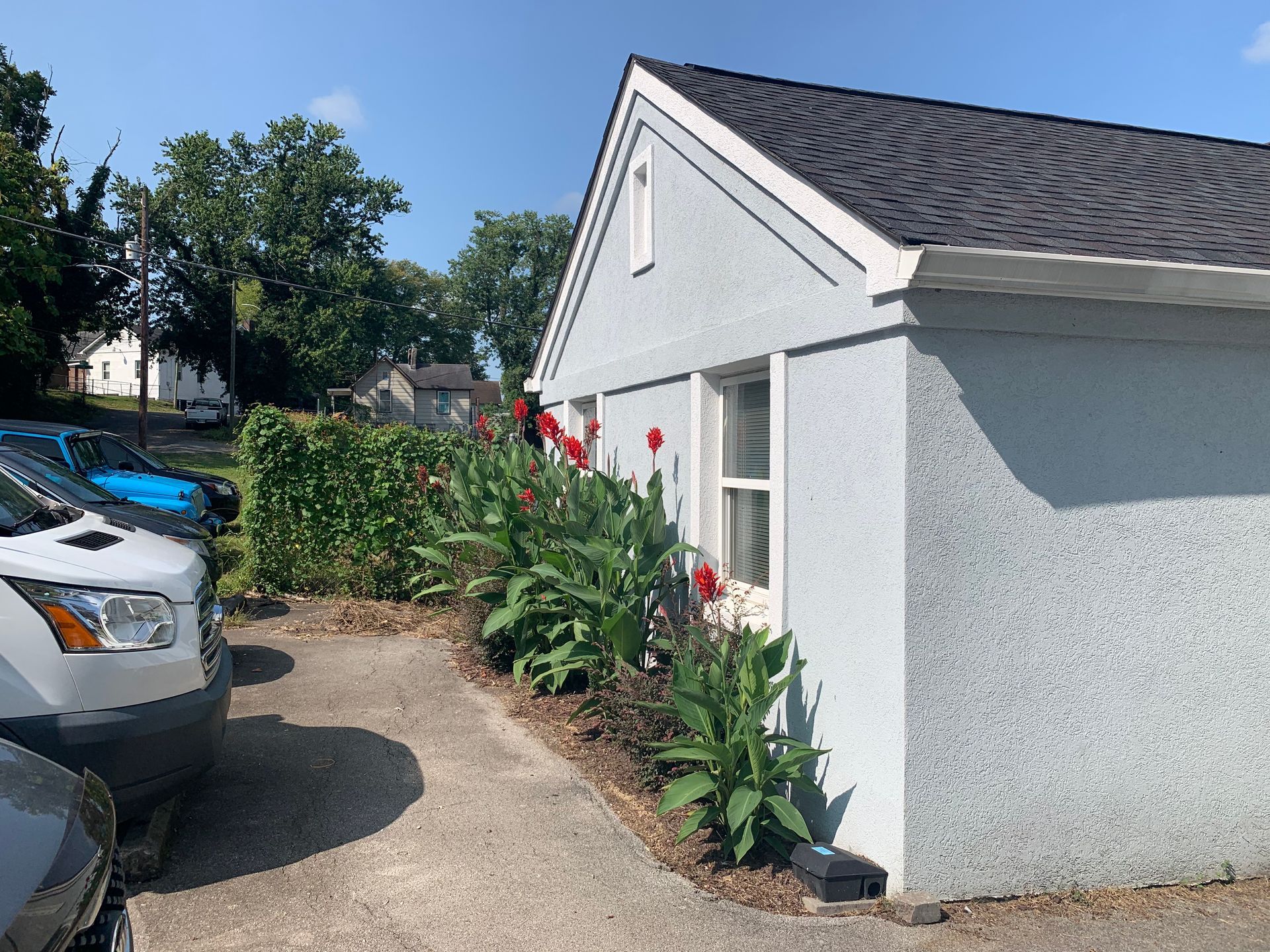 A white van is parked in front of a small house.