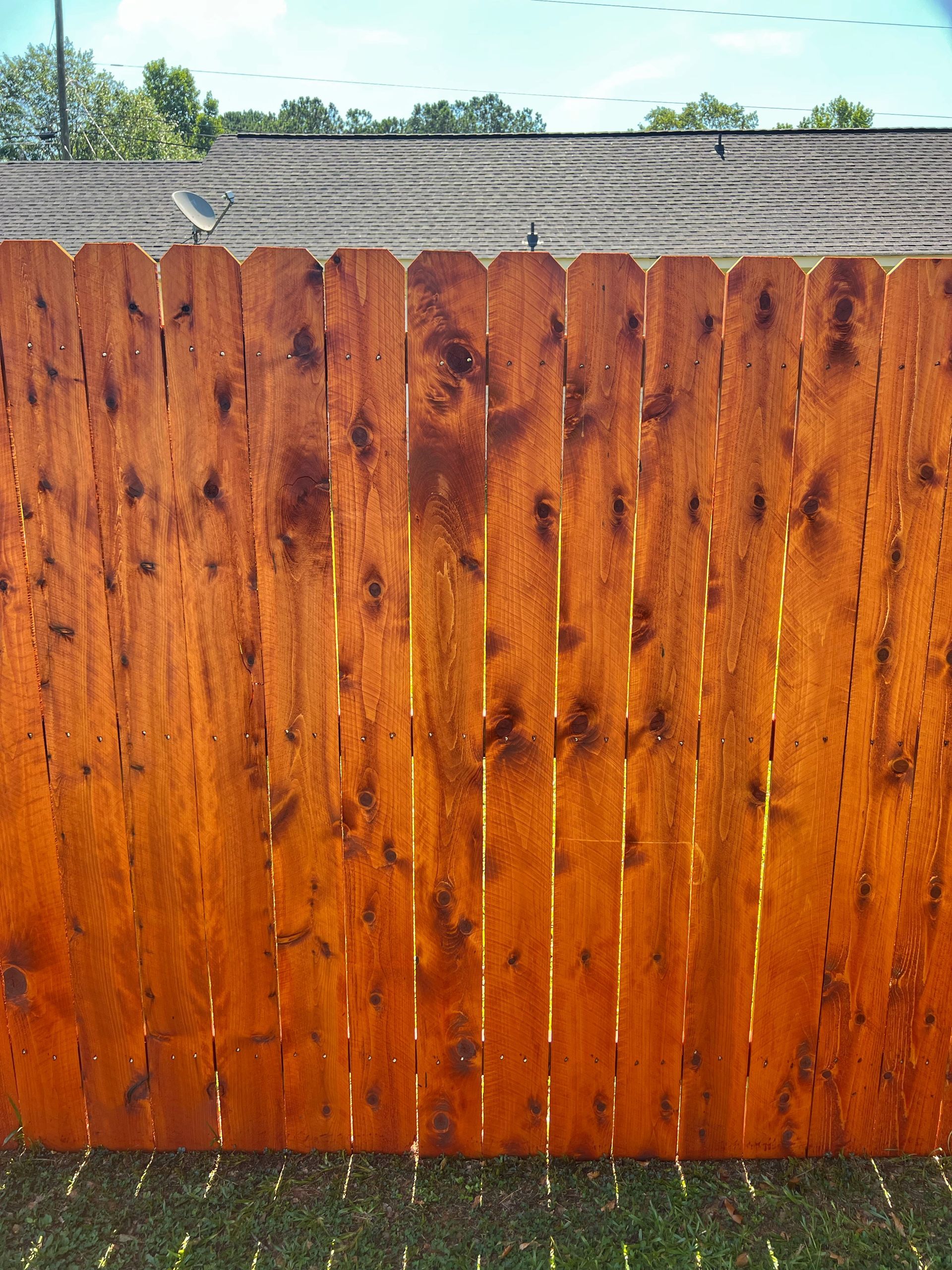 A wooden fence is sitting on top of a lush green field.