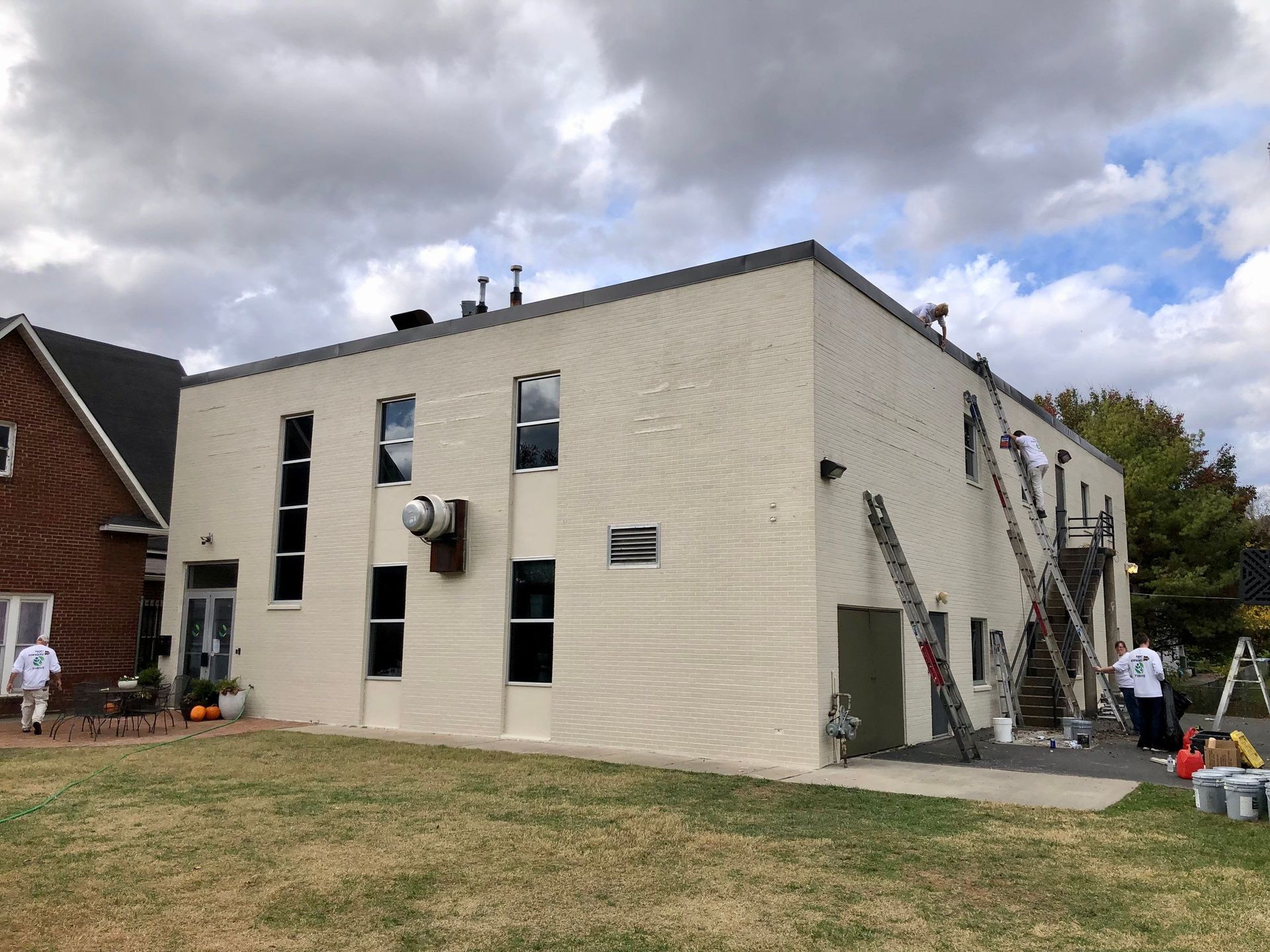 A large white building with a lot of windows is being painted.