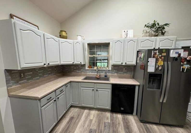 A kitchen with white cabinets and a stainless steel refrigerator.