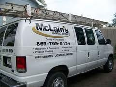 A white van with a ladder on top of it is parked in front of a house.