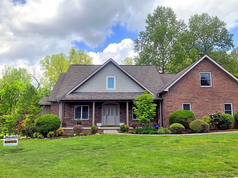 A large brick house with a large lawn in front of it.