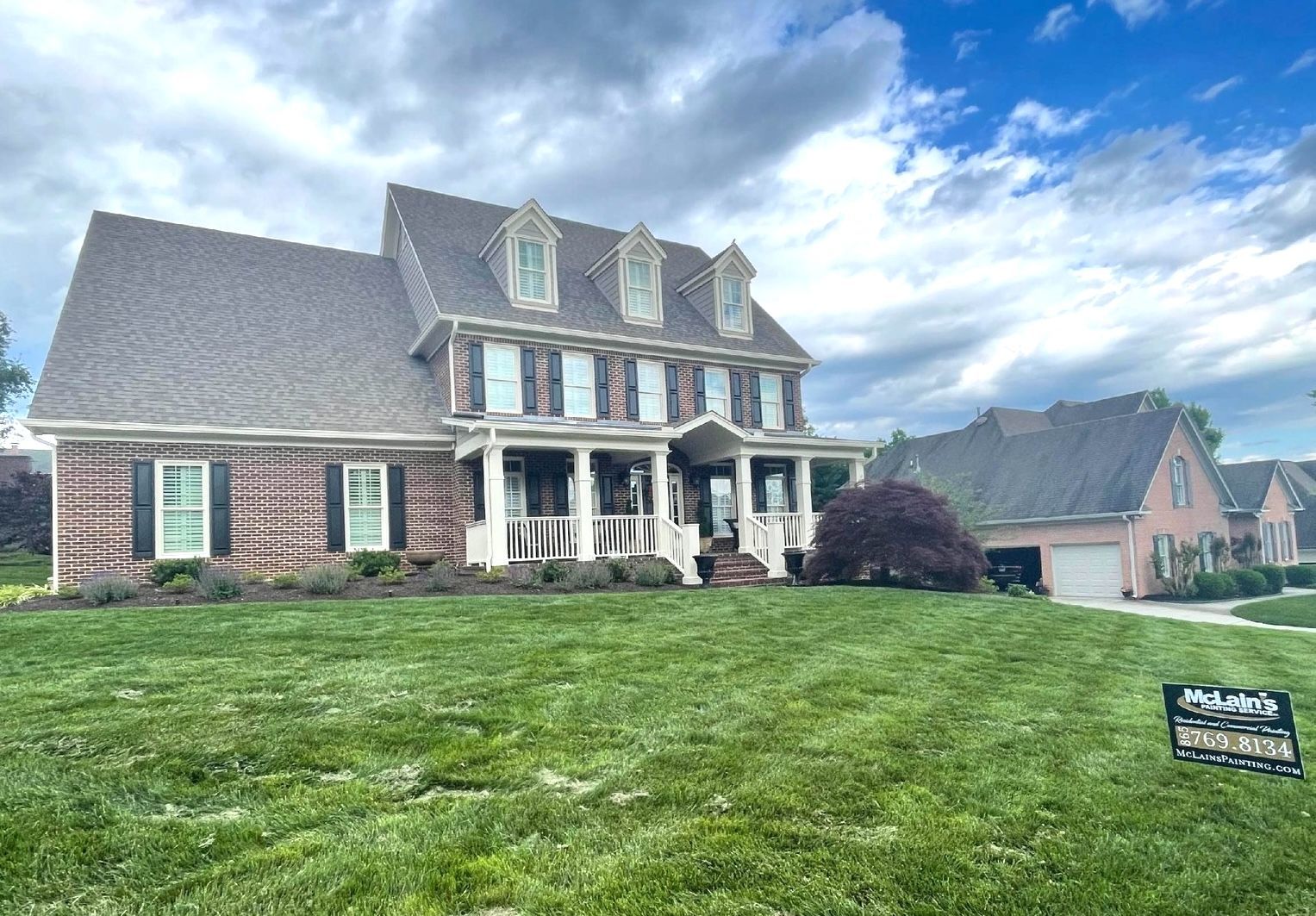 A large brick house with a large lawn in front of it.