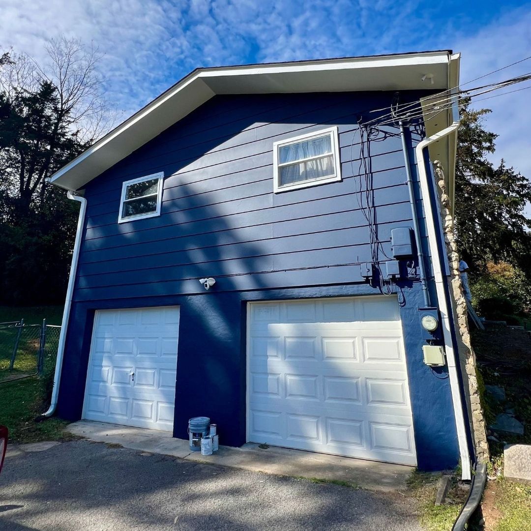 A blue house with white garage doors and windows