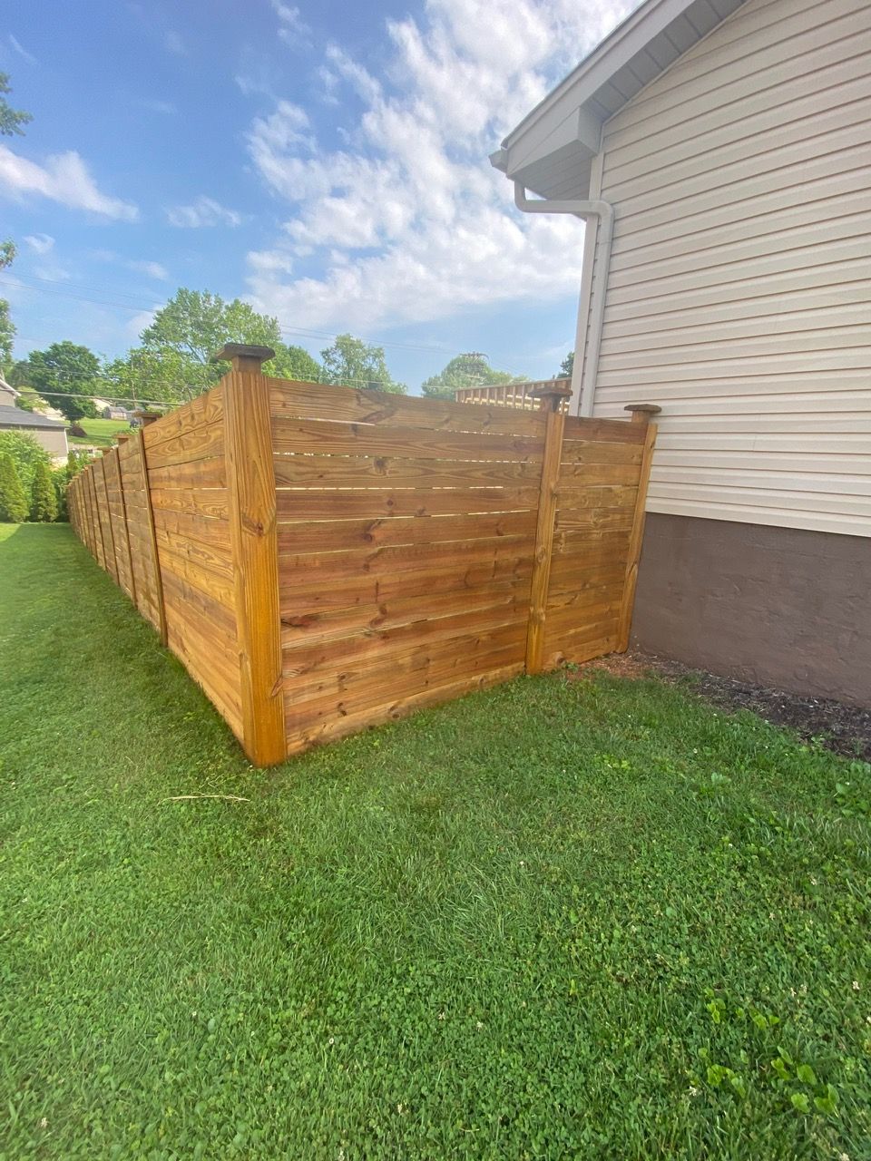 A wooden fence is in the backyard of a house.