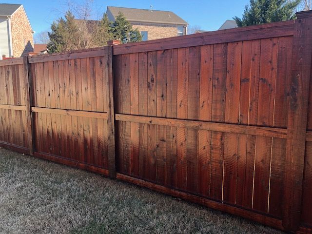 A wooden fence in a backyard with a house in the background.