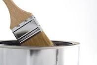 A paint brush is sticking out of a can of paint.