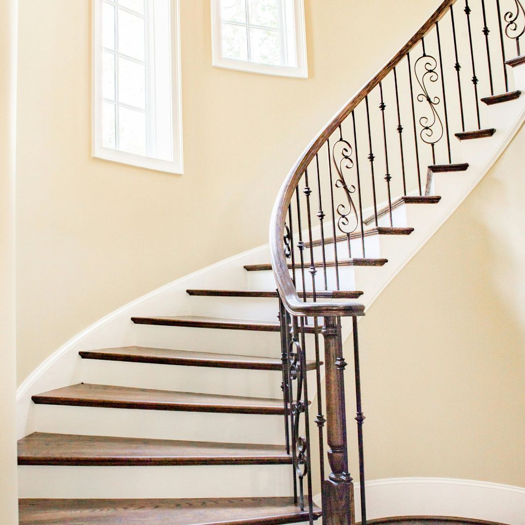 A spiral staircase with wooden steps and a wrought iron railing.