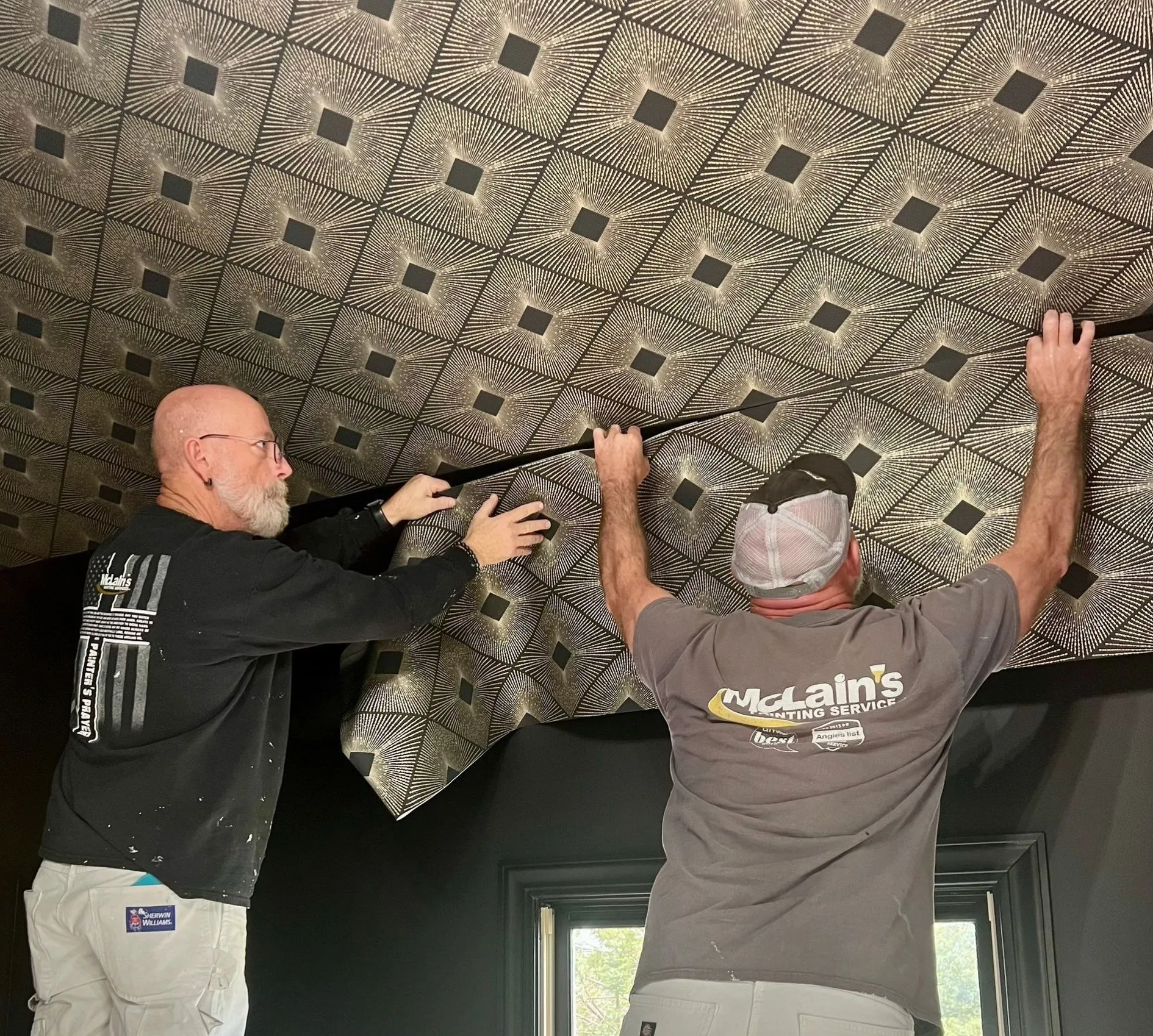 Two men are working on a ceiling in a room.