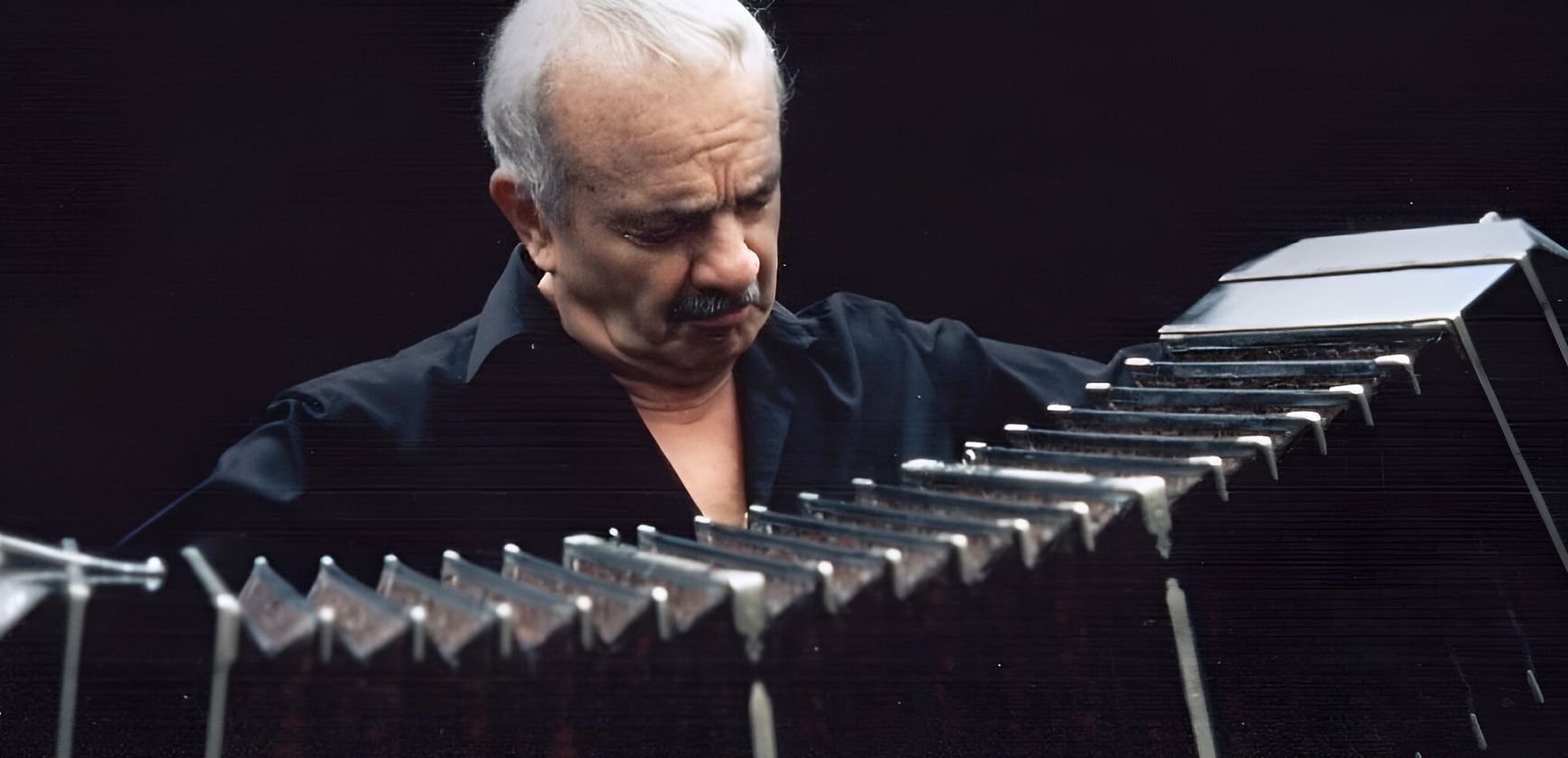 Hombre tocando un bandoneón, un tipo de acordeón de botones, sobre un fondo oscuro.