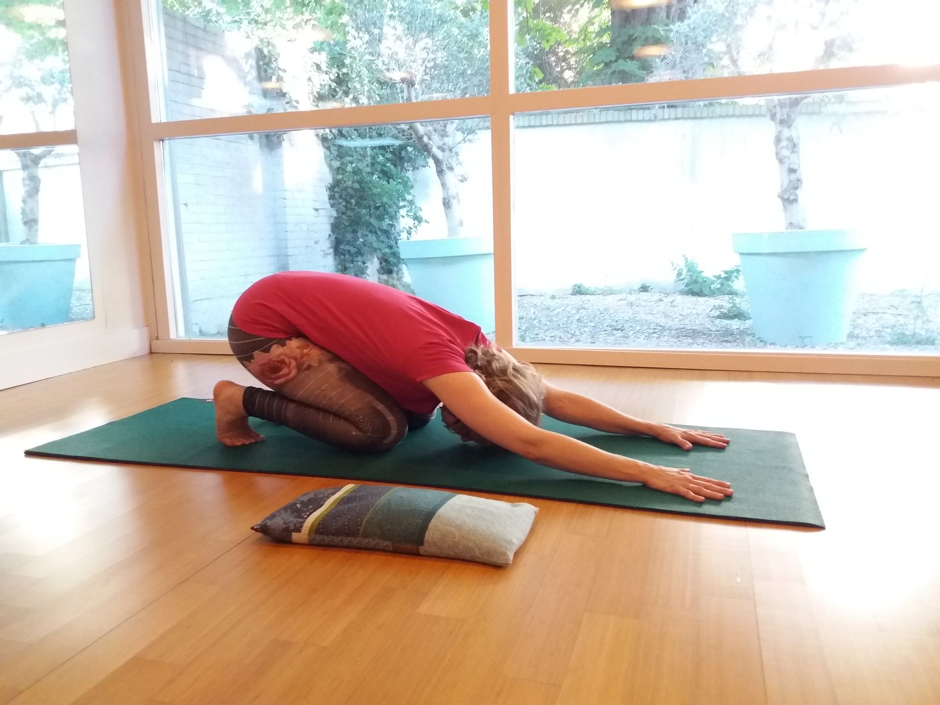 Yoga houding: actieve kindhouding met billen op de hielen, tenen omgekruld en armen uitgestrekt naar voren.