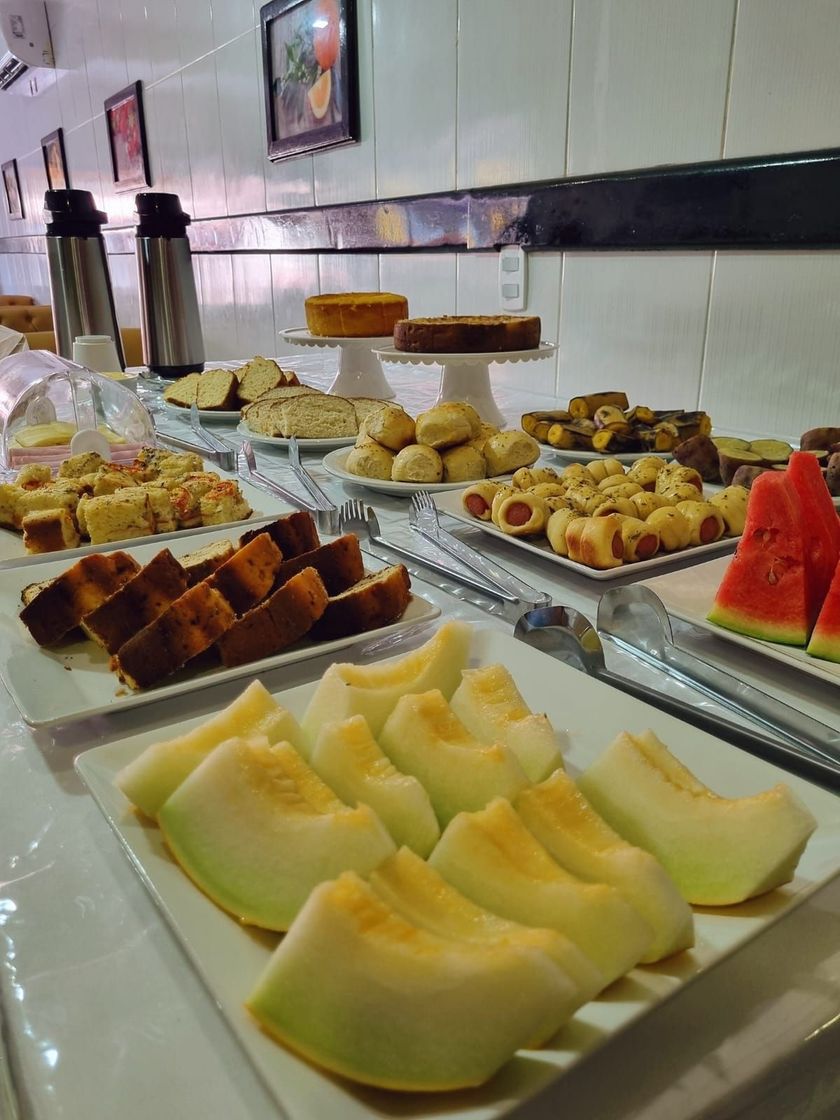 Melões e sobremesas variadas dispostas em um balcão de buffet em uma área de jantar iluminada.