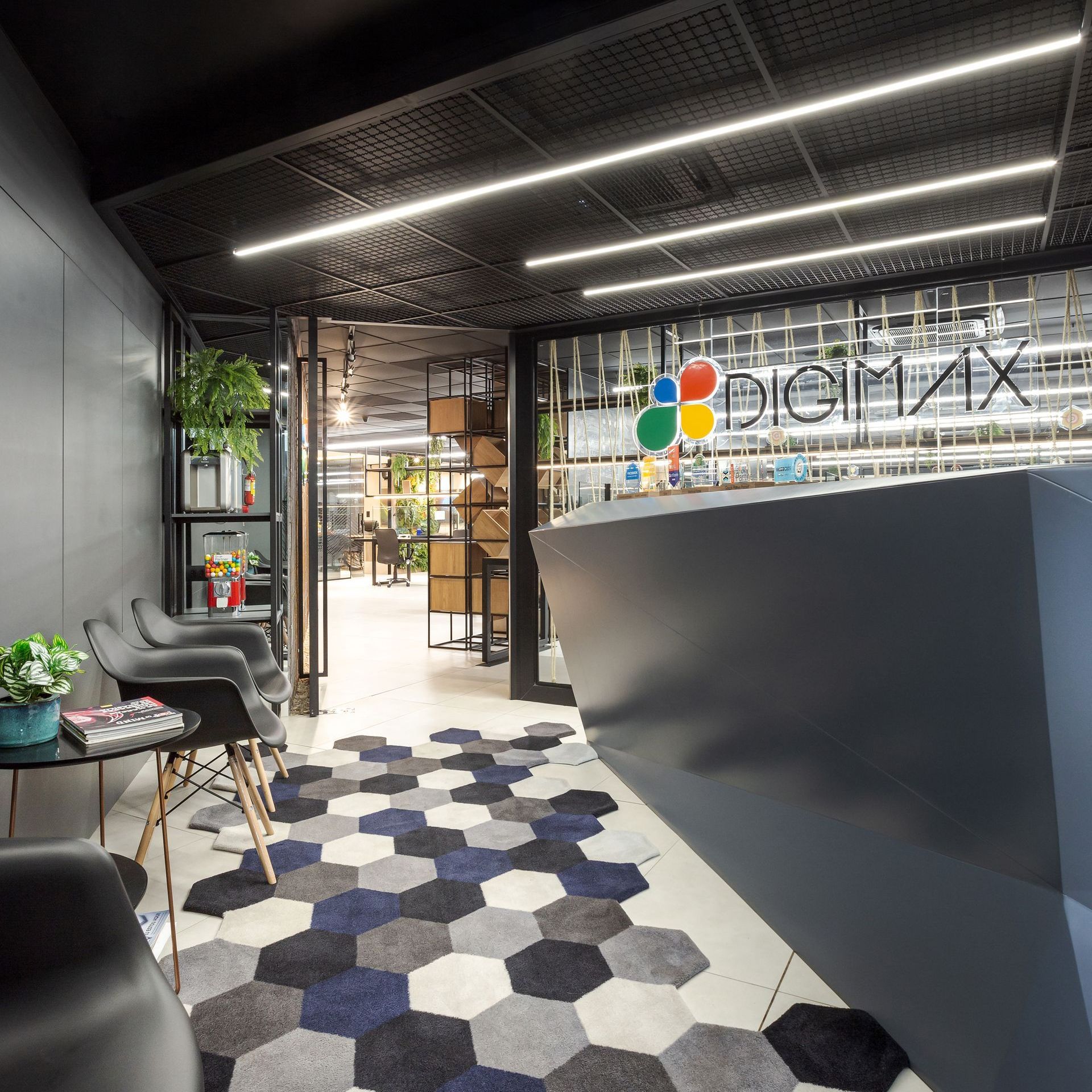 Hall de entrada moderno com tapete hexagonal, balcão de recepção preto e entrada de vidro.