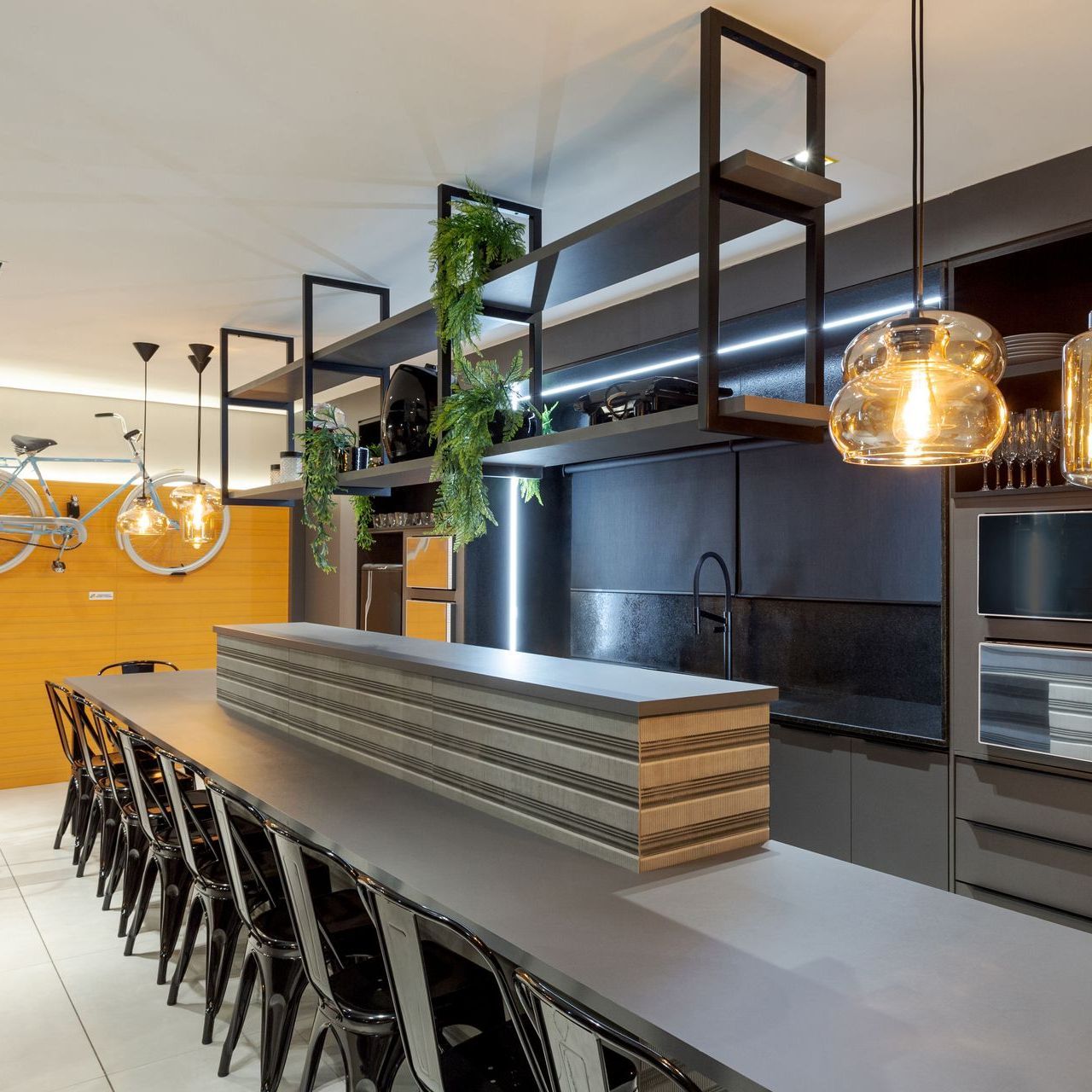 Cozinha moderna com ilha central, prateleiras abertas e luminárias pendentes em tons quentes.
