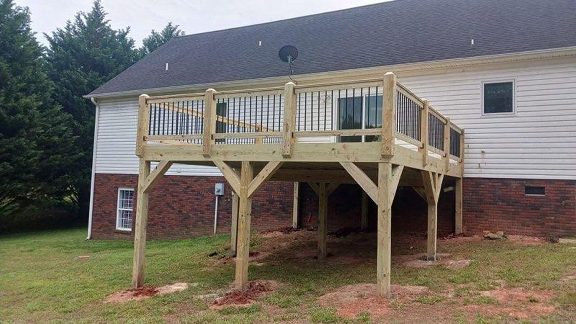 A wooden deck is sitting in front of a brick house.