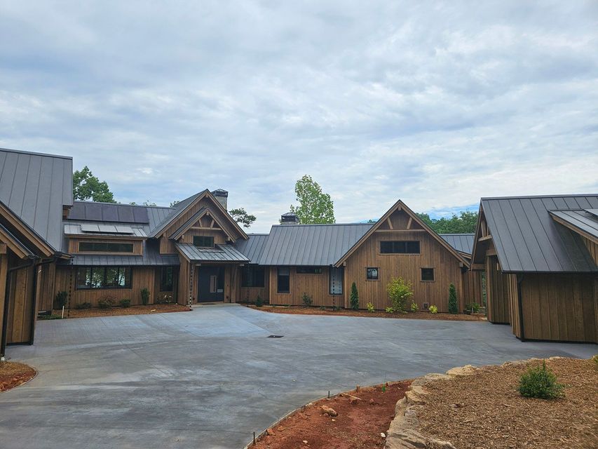 A large wooden house with a metal roof and a driveway in front of it.