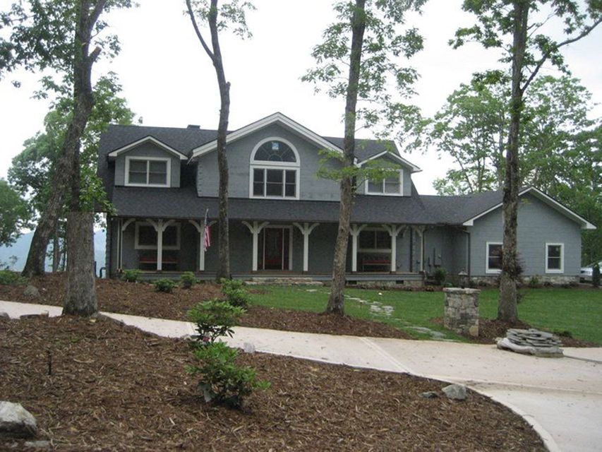 A large gray house with a black roof is surrounded by trees