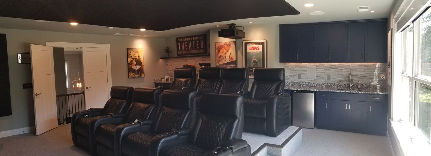A home theater with black leather seats and a projector.