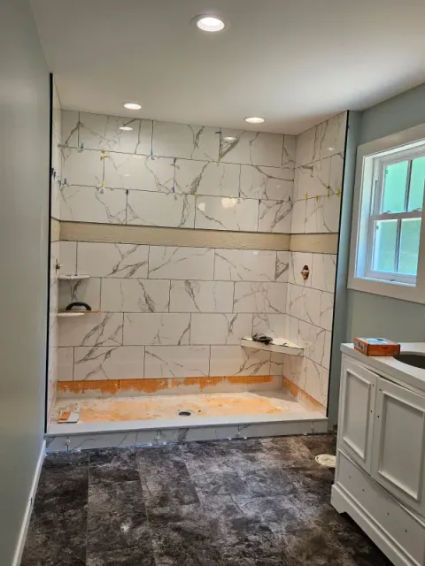 A bathroom with a walk in shower and a sink.