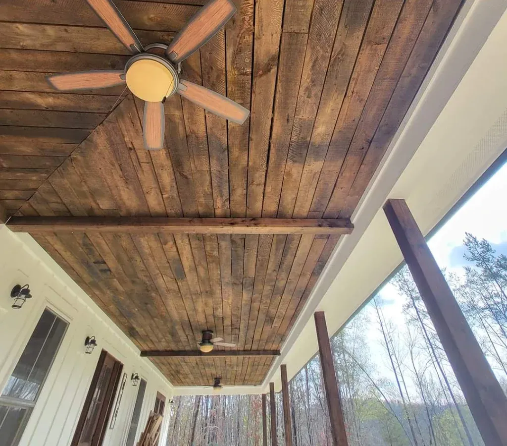 A porch with a wooden ceiling and a ceiling fan