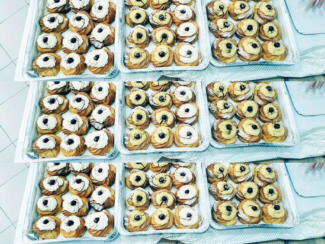 Diversi vassoi colmi di tanti piccoli pasticcini rotondi ricoperti di glassa bianca e sormontati da un singolo frutto di bosco scuro.