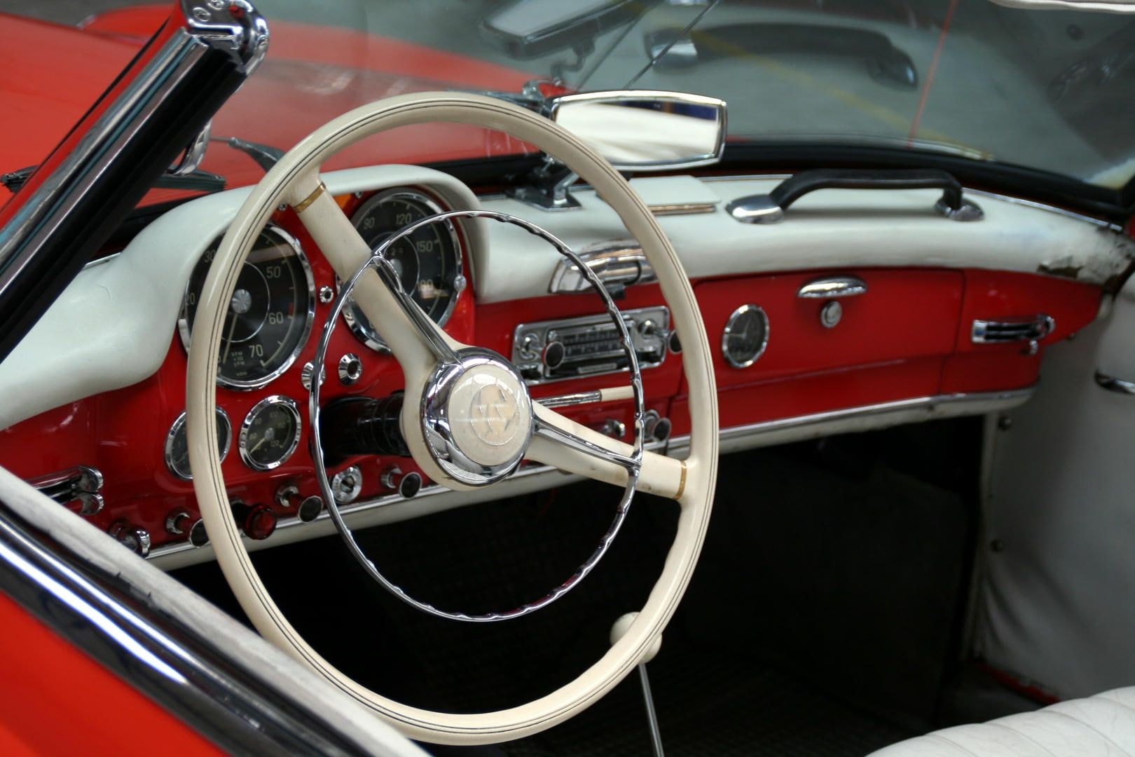 Red car interior with cream-colored steering wheel, dashboard, and accents.