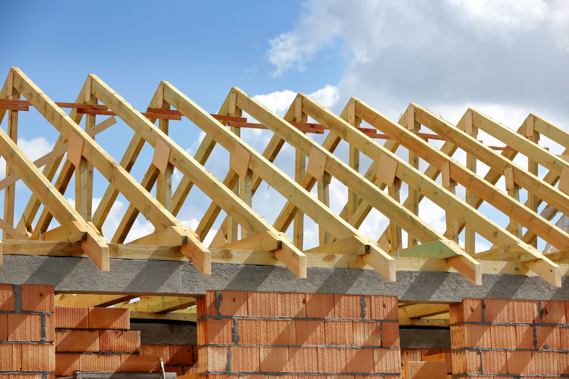 View of a house roof being constructed, with many timber roof trusses.