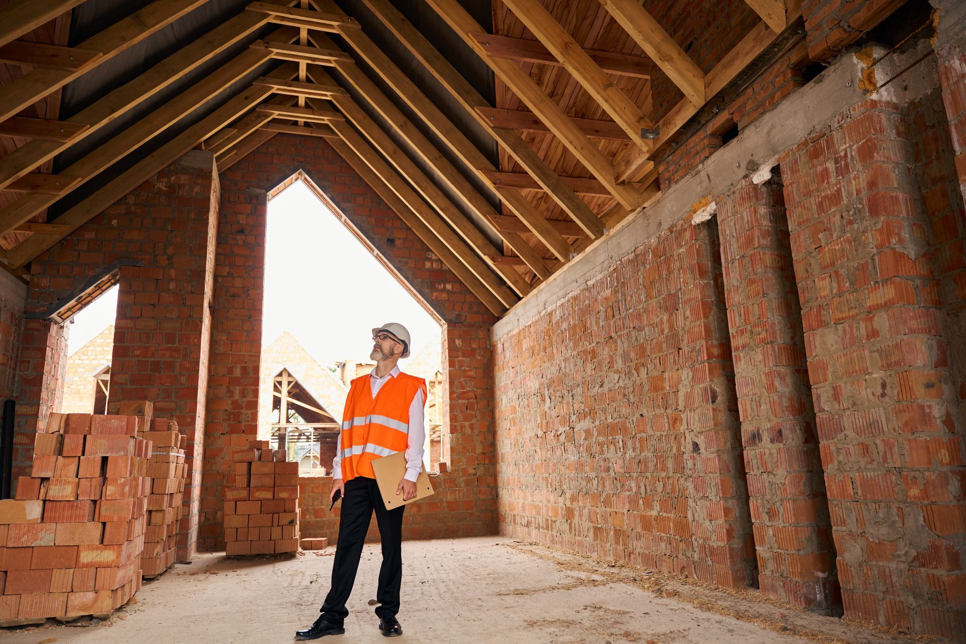 Construction superintendent inspecting timber roof trusses from inside the building.
