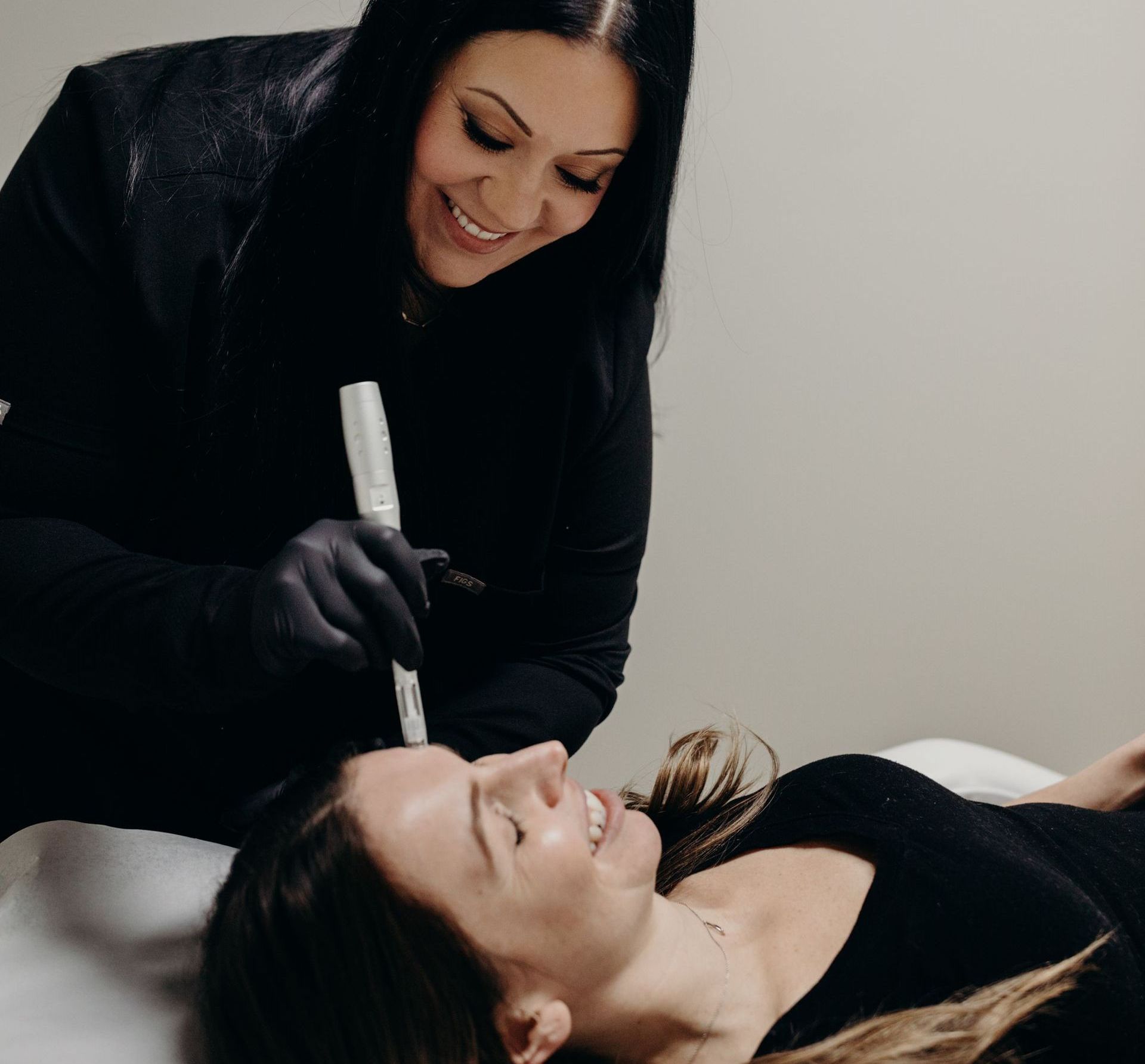 A woman is smiling while a woman is laying on a bed.