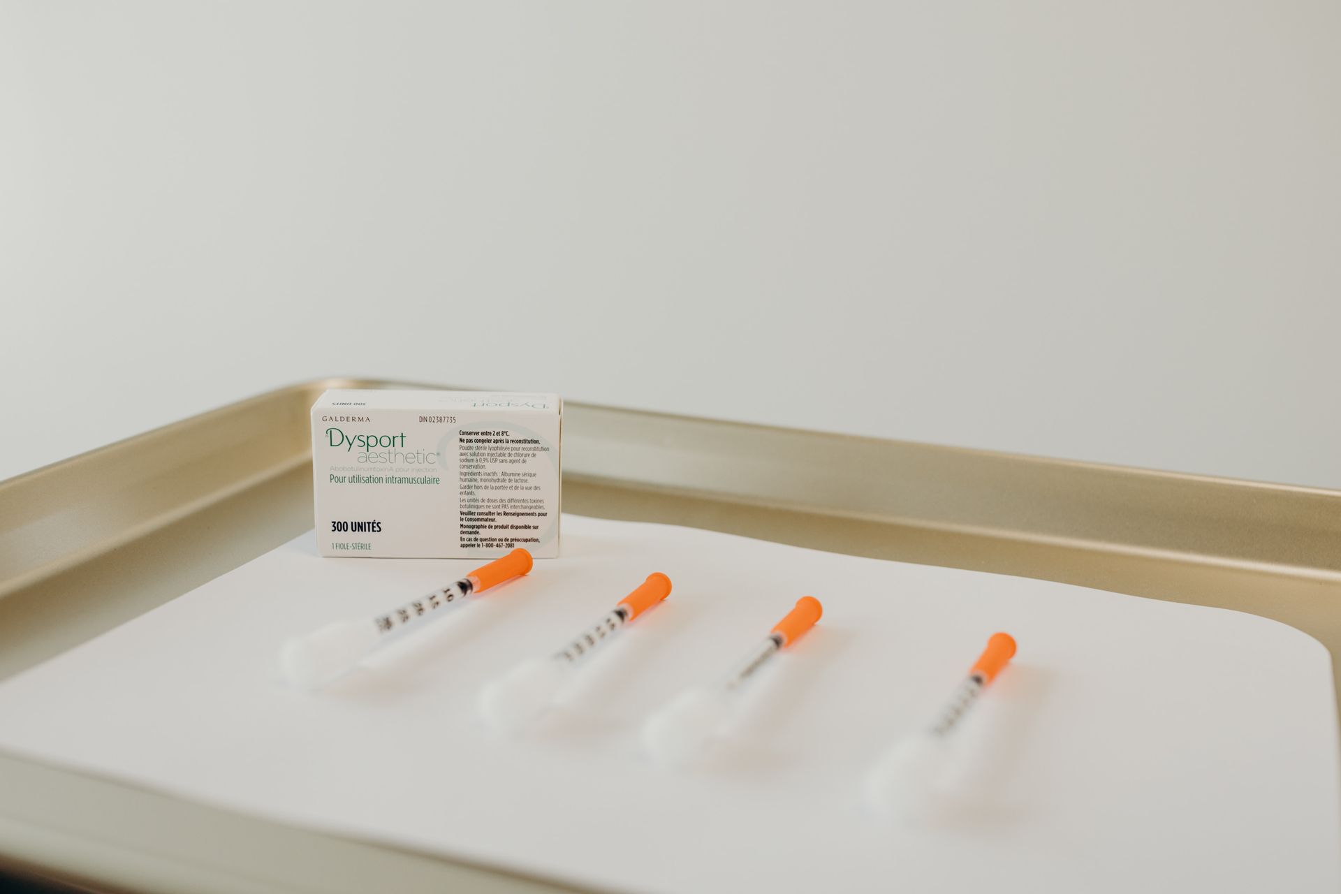 Four syringes are sitting on a table next to a box of pills.