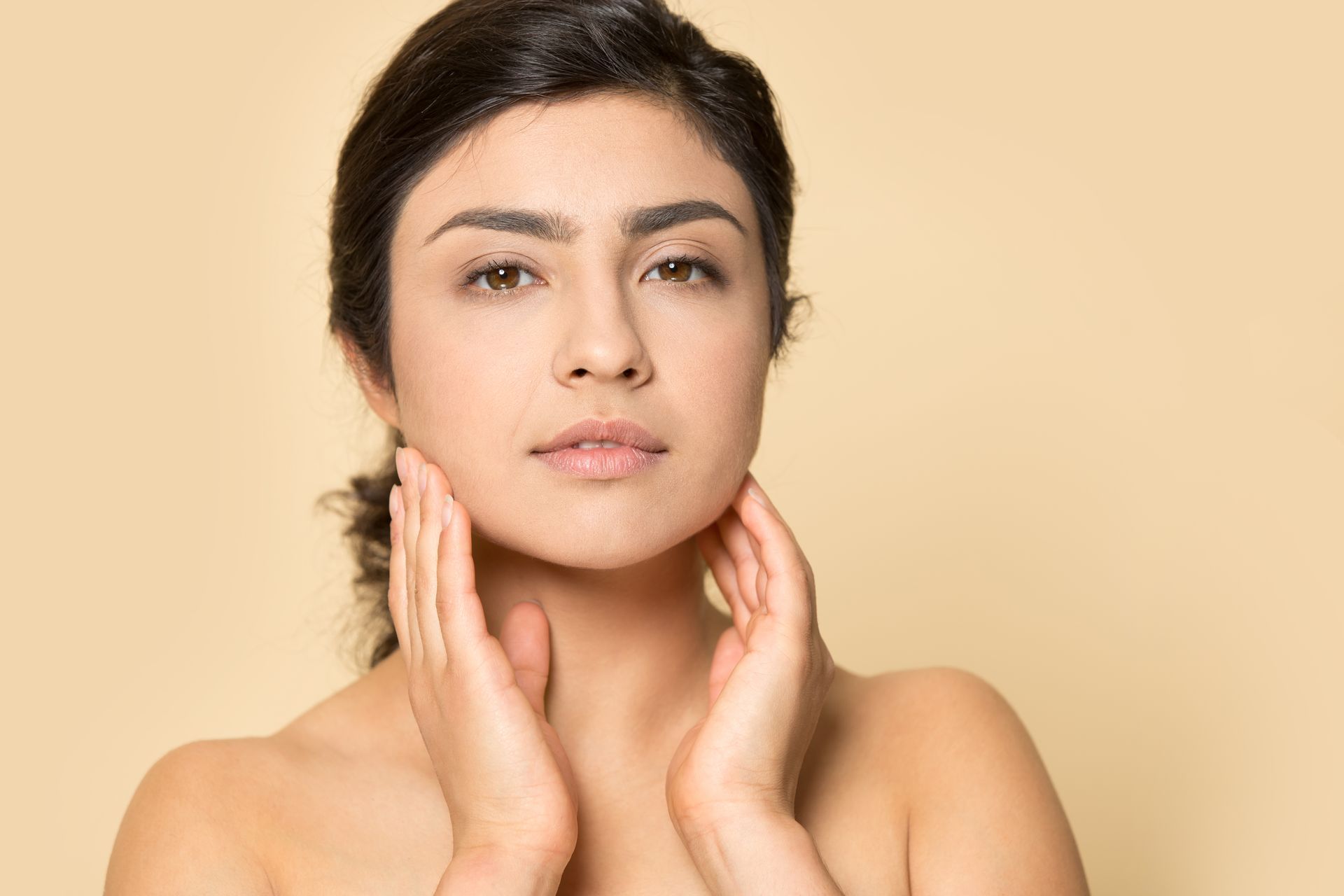 A woman is slightly smiling and touching her face