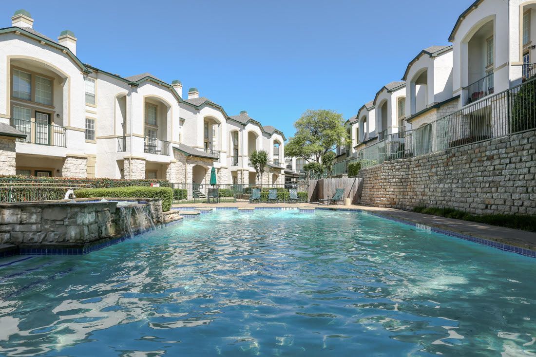 Community pool with surrounding apartments and clear blue sky