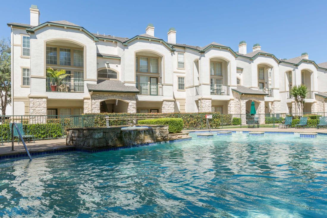 Outdoor pool area with apartments in the background.