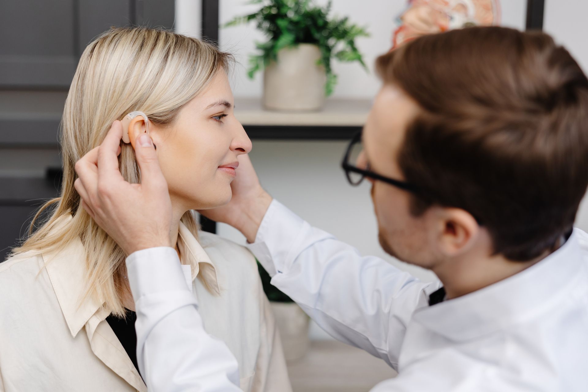 A doctor is putting a hearing aid in a patient.