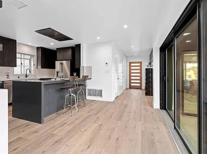 Modern kitchen with black island and glass sliding doors.