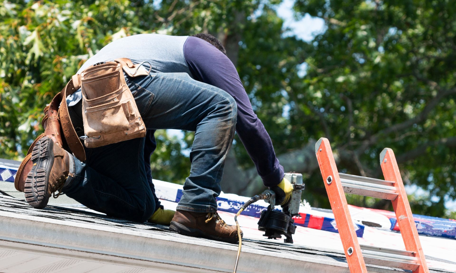 Roofing contractor using a nail gun to install asphalt shingles