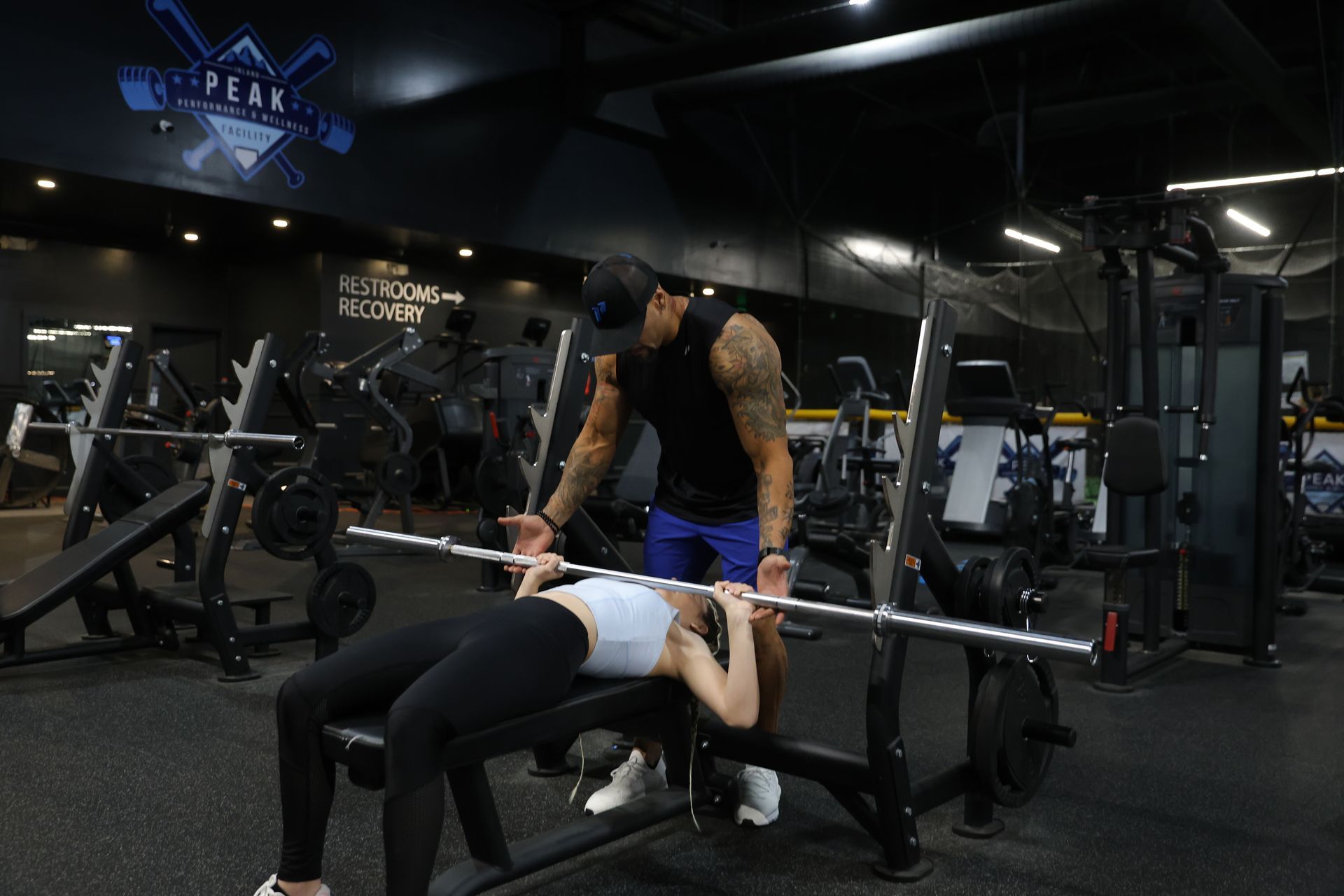 A man is sitting on a bench in a gym holding a blue bottle