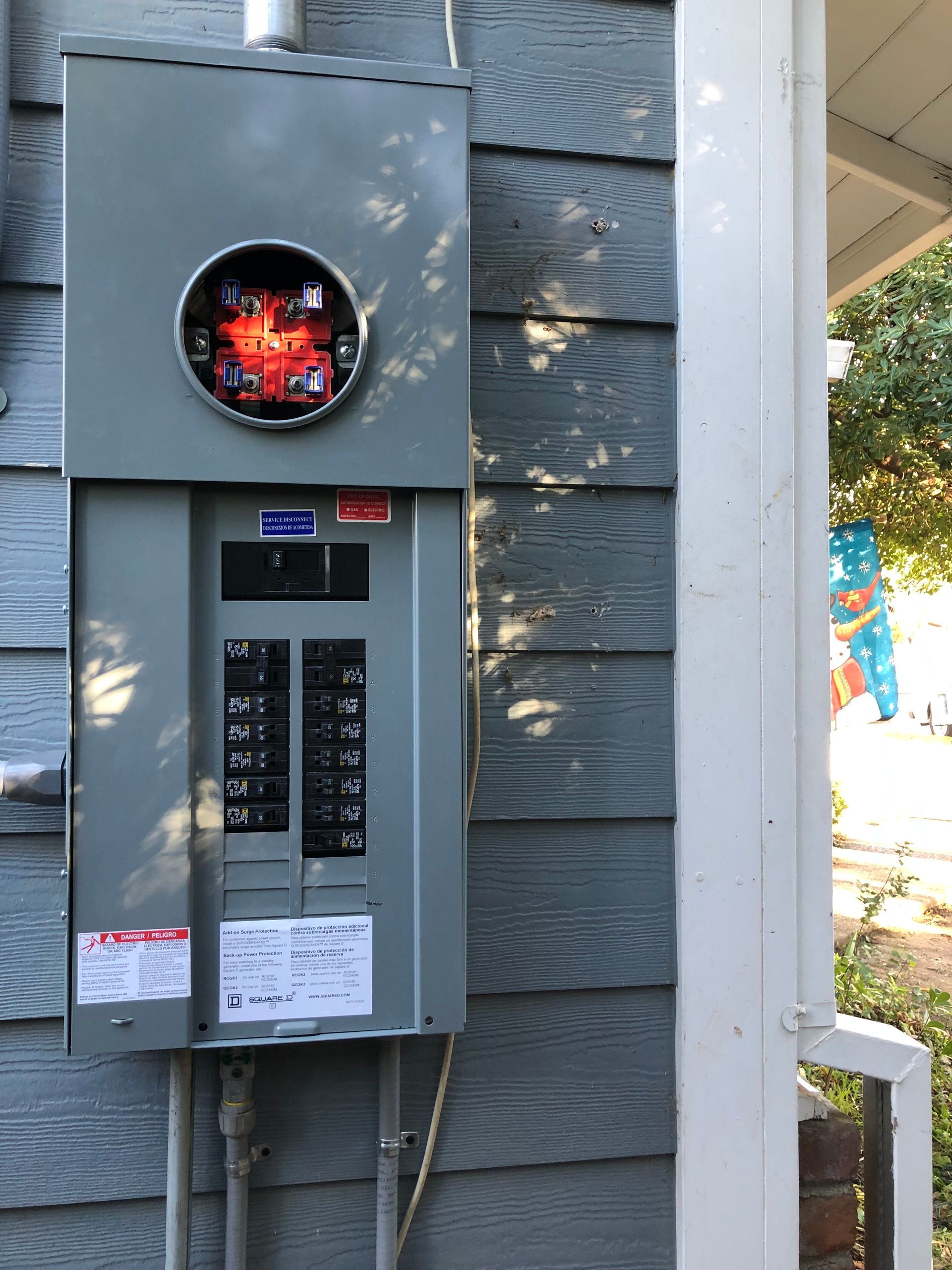 Gray outdoor electrical panel with a glowing red heater/firebox opening mounted on a blue-gray wall