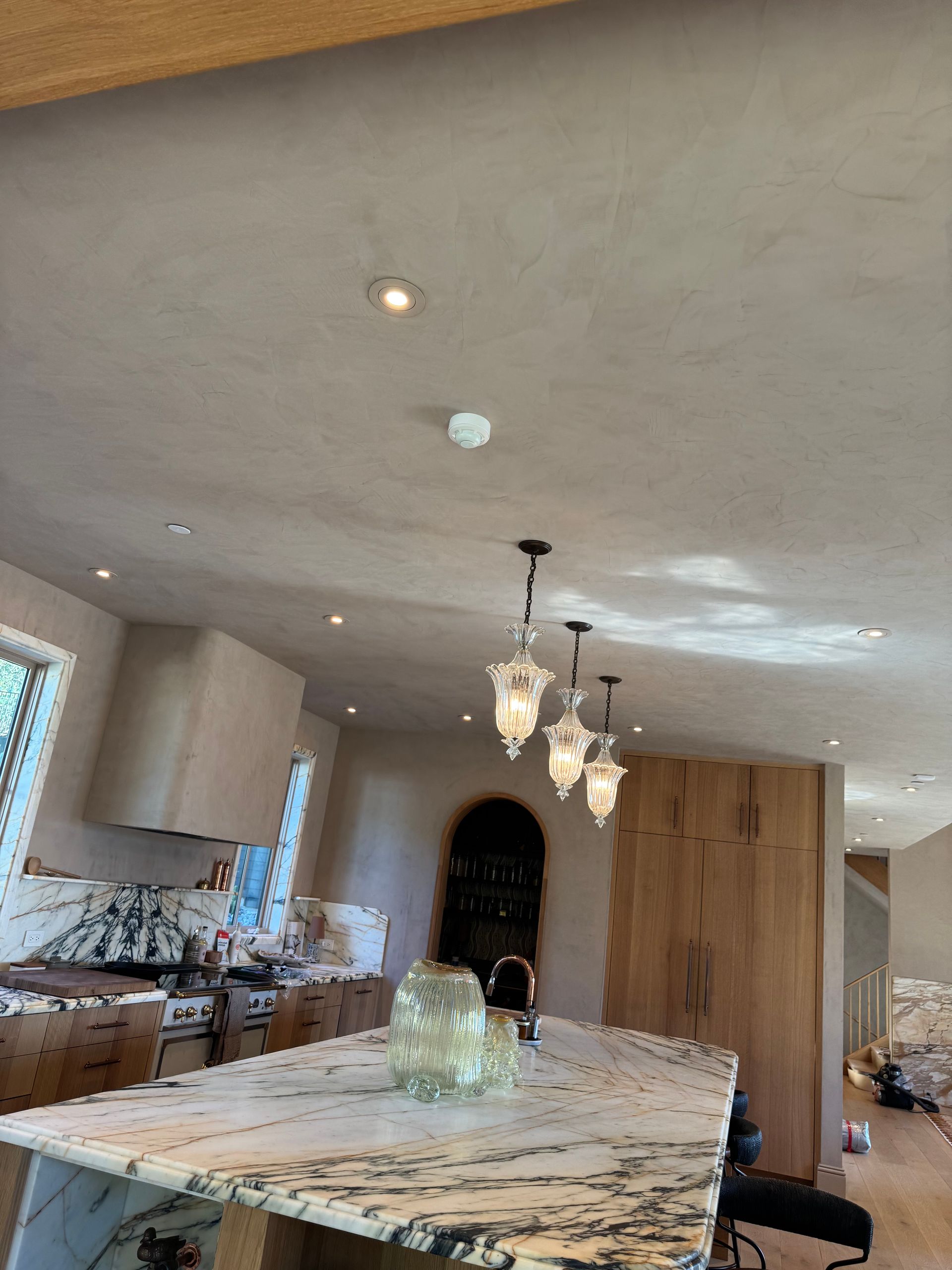 Bright kitchen with marble island, pendant lights, wood cabinets, and recessed ceiling lights