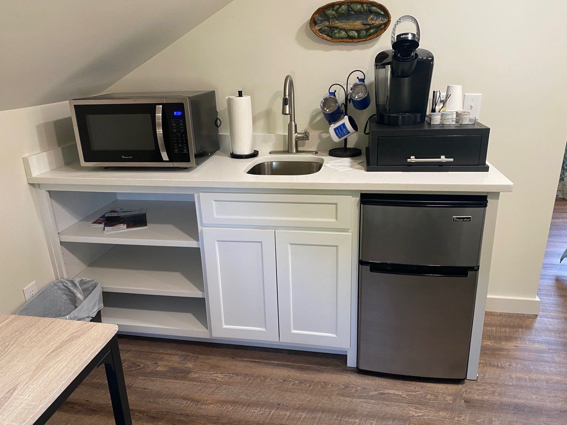 Small kitchenette with a microwave, sink, cabinets, and a mini-fridge. 