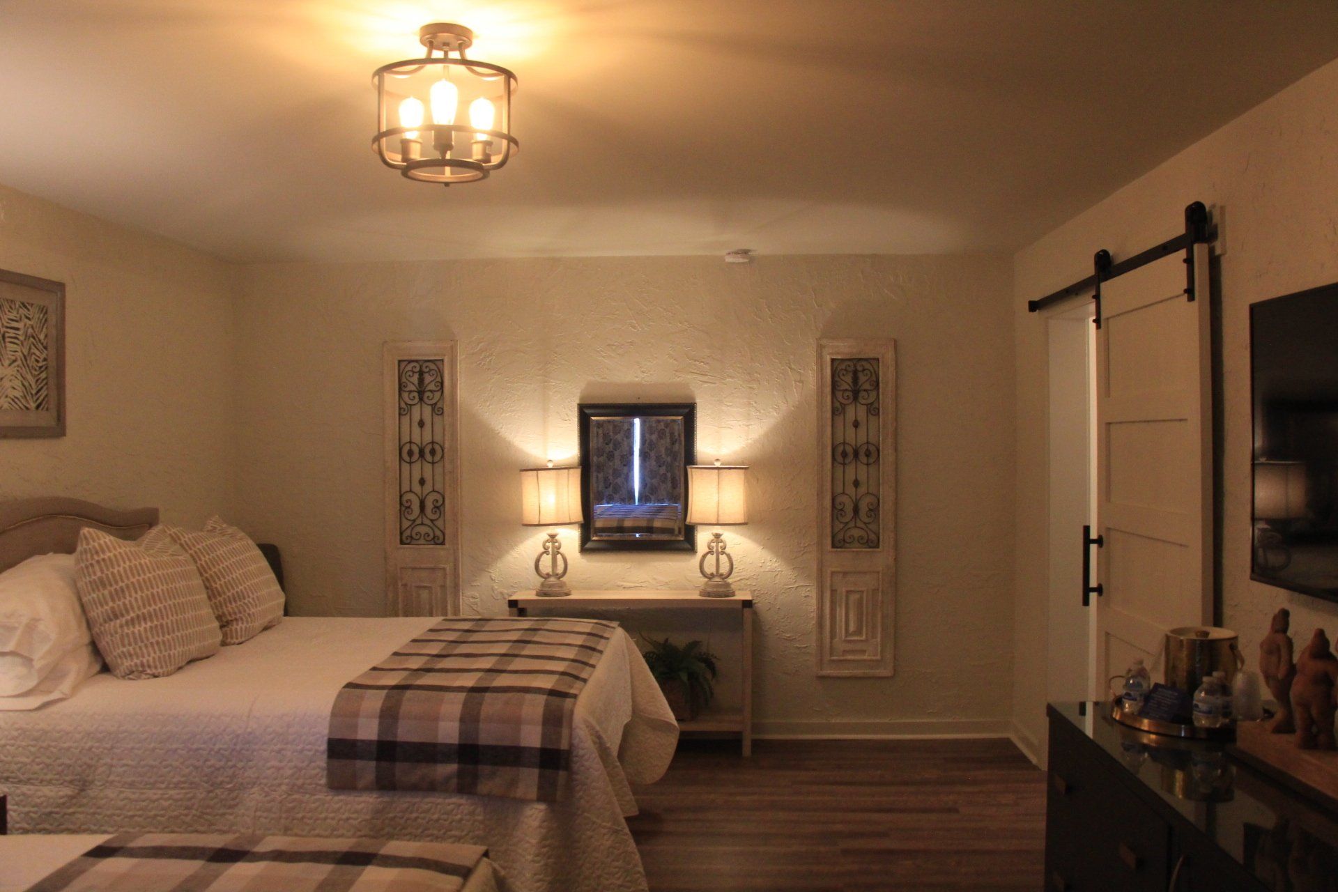 Bedroom with two beds, a sliding barn door, and decorative lighting fixtures.