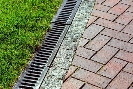 Iron drainage net between paving slab and green lawn