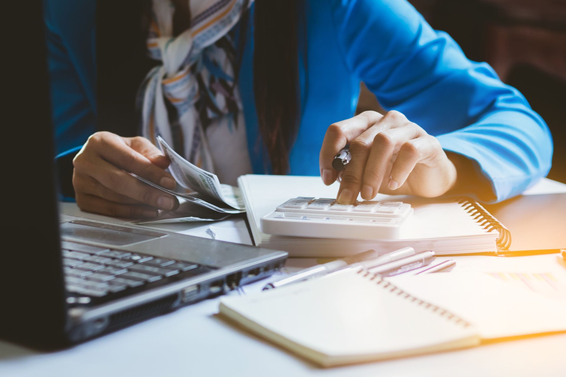A woman is using a credit card and a calculator at a desk.