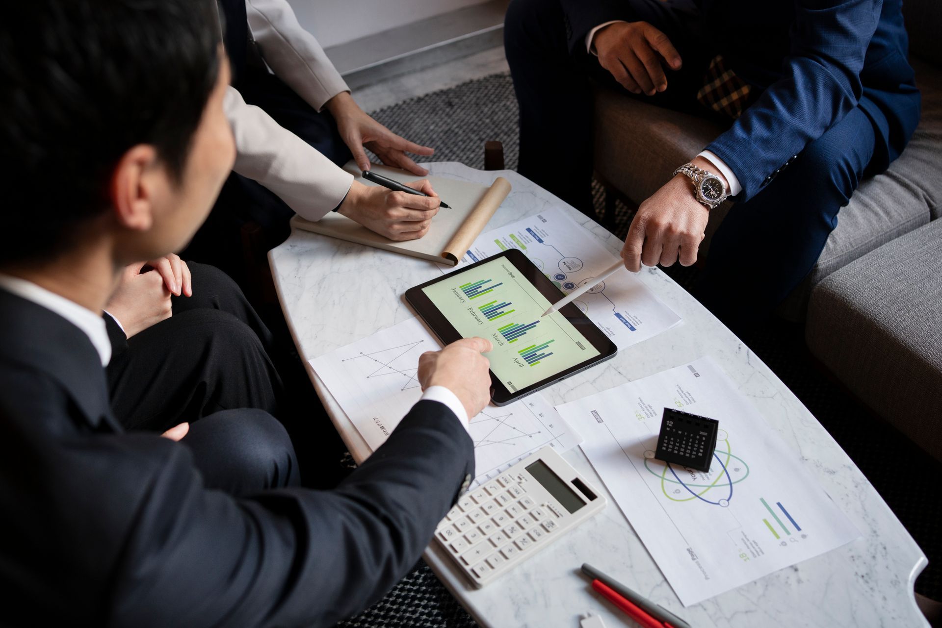 Colleagues reviewing charts and a tablet during a business meeting at a table
